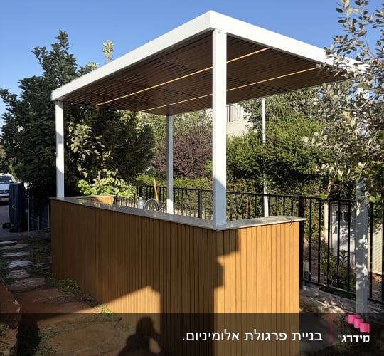 פרגולת אלומיניום לבנה קטנה עם חיפוי דמוי עץ מעל דלפק בחצר
